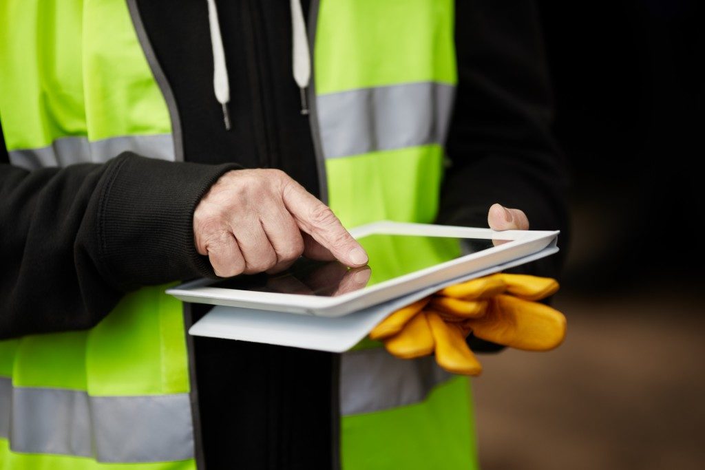 man with work vest using a tablet